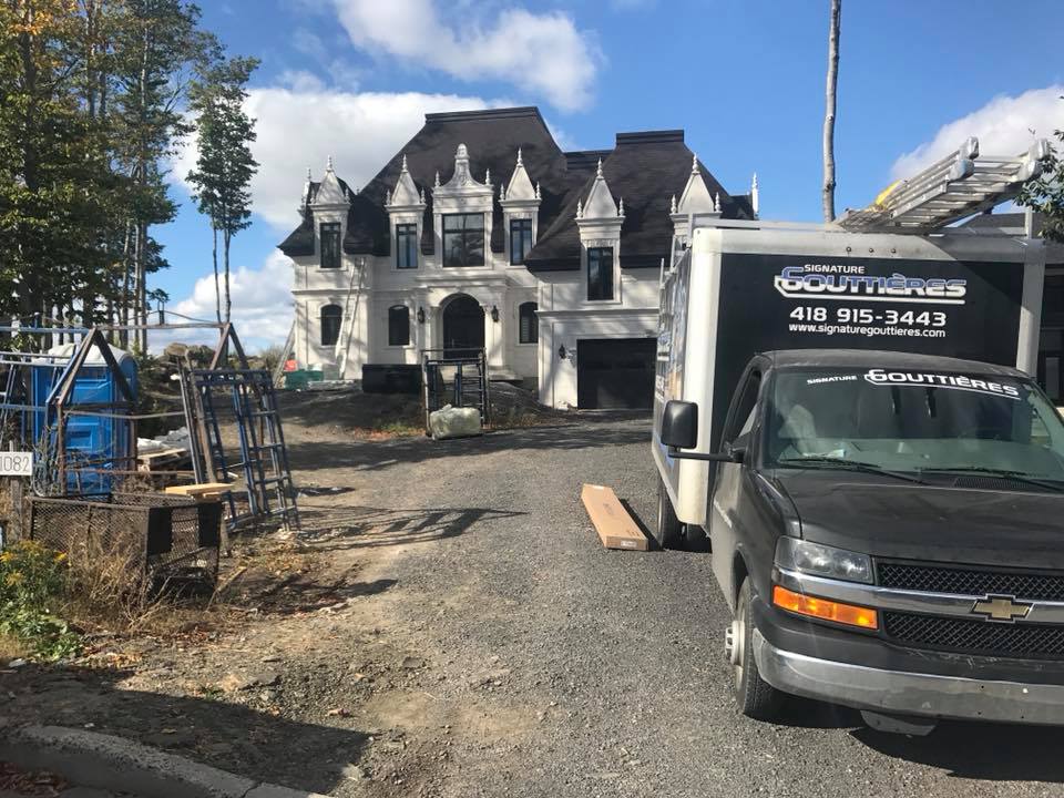Véhicules de service stationnés lors de travaux d’installation de gouttières sur la Rive-Sud et la Rive-Nord de Québec